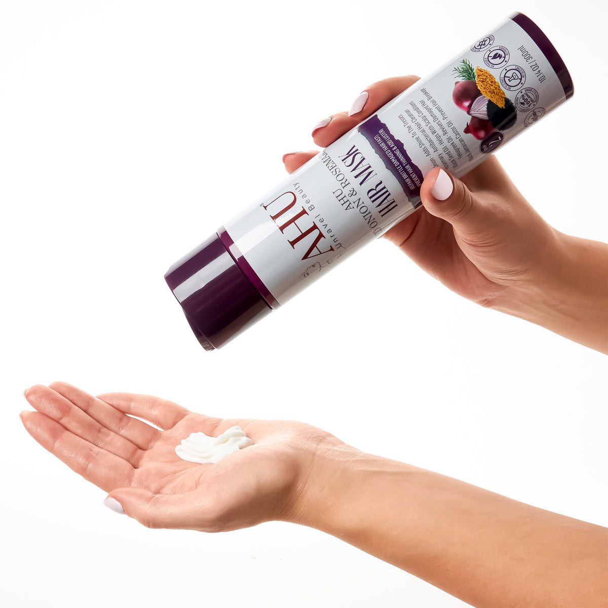 Hands holding the AHU Red Onion & Rosemary Hair Mask bottle and dispensing white cream onto an open palm