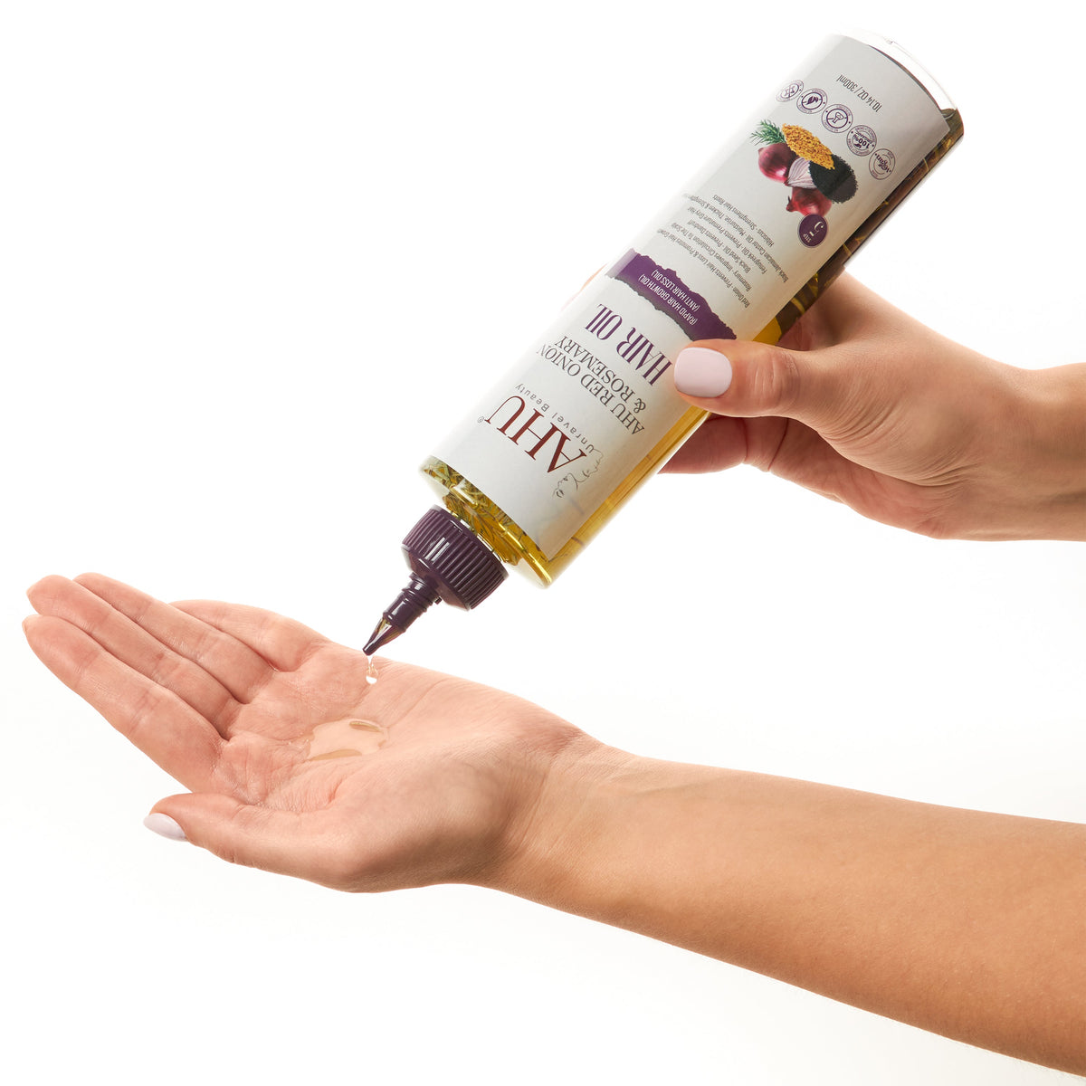 Hands holding the AHU Red Onion & Rosemary Hair Oil bottle and dispensing oil onto an open palm