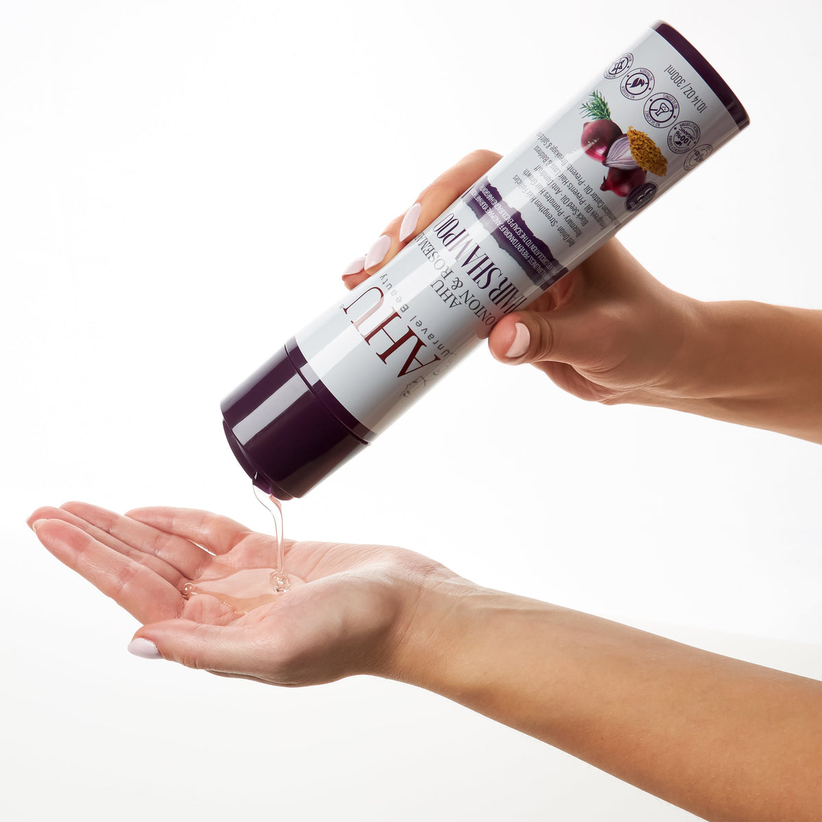 Hands holding the AHU Red Onion & Rosemary Hair Shampoo bottle and dispensing shampoo onto an open palm