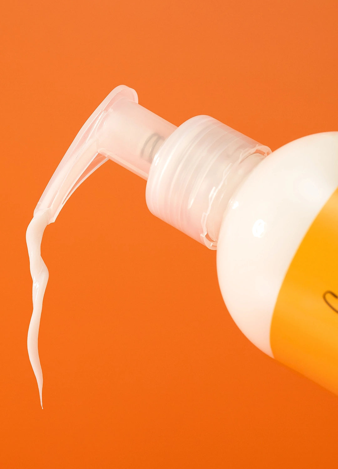 Close-up of the white pump top with a ribbon of white cream on an orange background