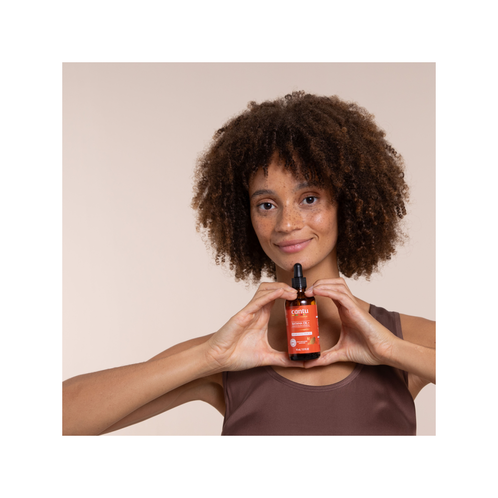 Model holding Cantu Ultra Moisture Nourishing Hair Oil