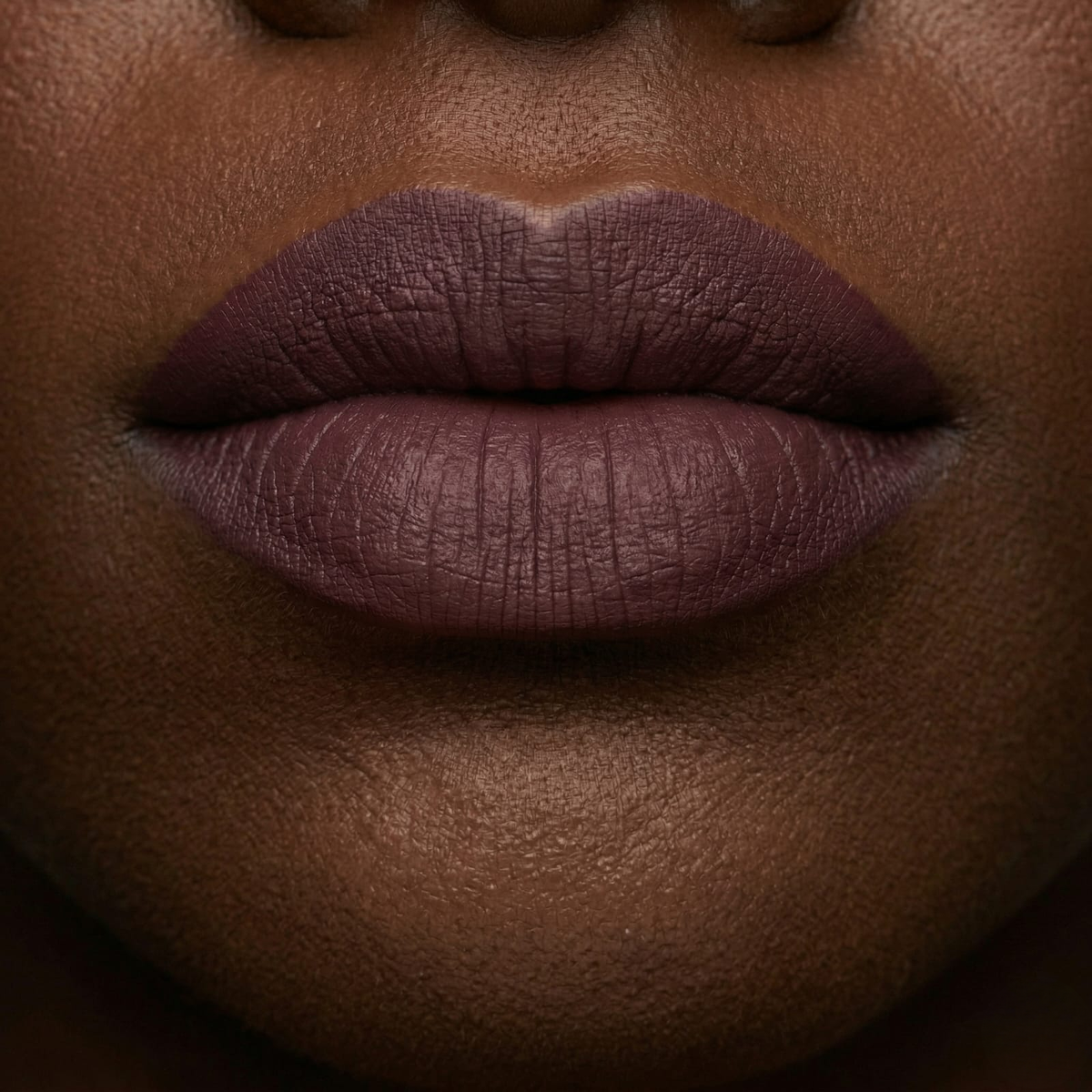 Close-up of lips wearing a deep plum matte lipstick
