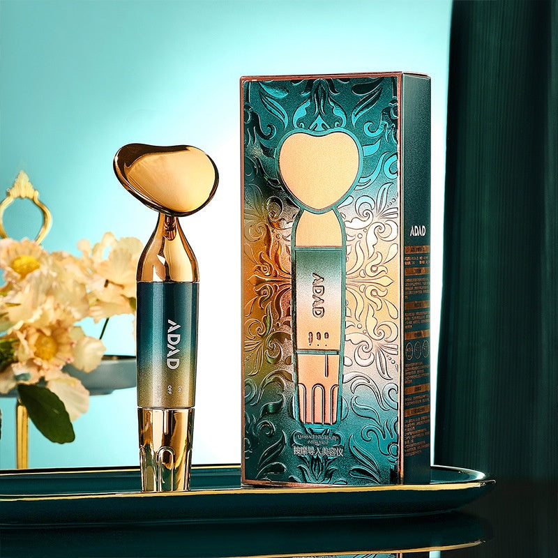 Heart-headed gold and teal ADAD massager beside its gold patterned gift box