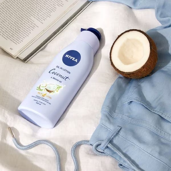 Nivea Coconut lotion bottle beside coconut and book