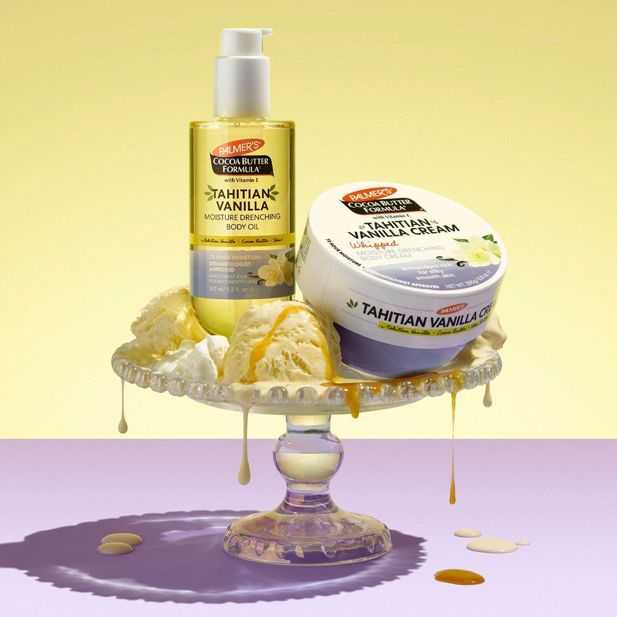 Tahitian Vanilla body oil beside a Tahitian Vanilla cream tub on a glass cake stand with ice cream scoops and almond slices